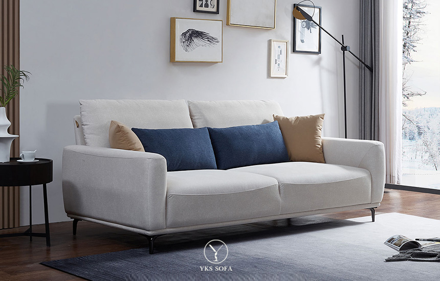 冬季客廳以米白布沙發為主體，搭配焦糖棕與霧藍靠枕，營造柔和溫暖的居家氛圍。