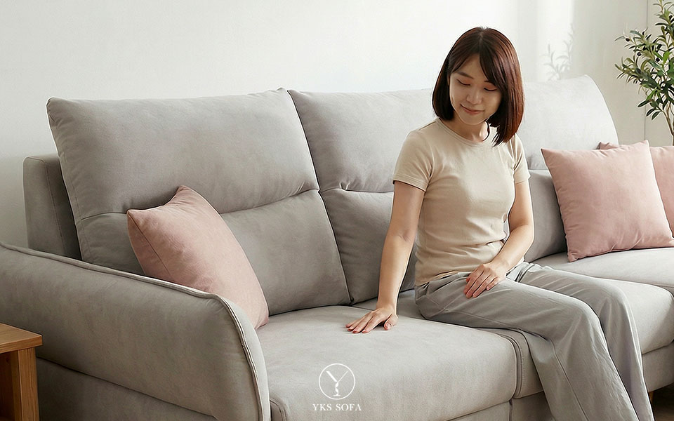 女生坐在沙發上用手觸摸布料，體驗沙發表布觸感與材質細節，強調沙發面料的重要性